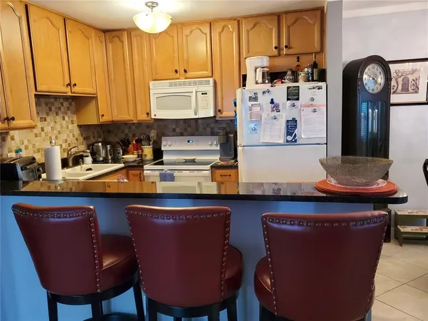 a kitchen with stainless steel appliances granite countertop a table chairs stove and cabinets