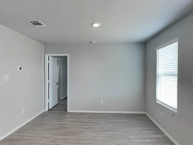 an empty room with wooden floor and windows