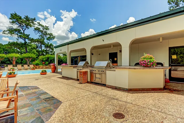 a view of swimming pool with outdoor seating and trees in the background