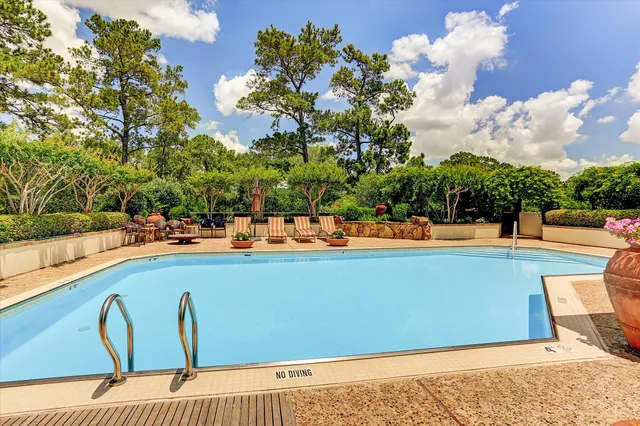 a view of swimming pool with outdoor seating and trees in the background