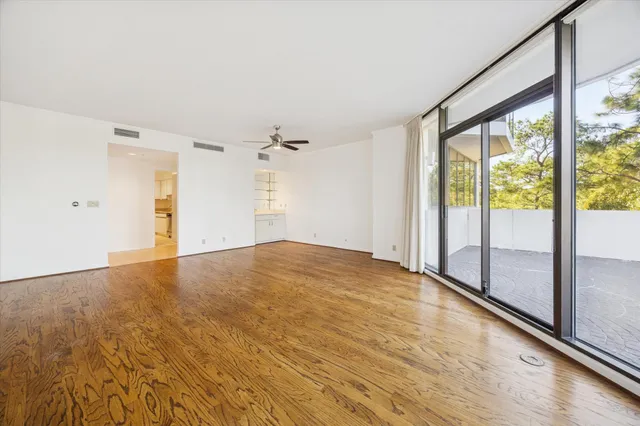 a view of empty room with wooden floor and fan