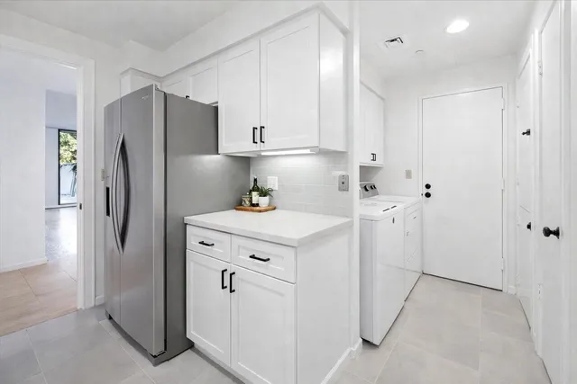 a kitchen with white cabinets and refrigerator