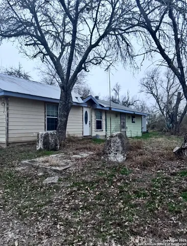a view of a house with a yard and large tree