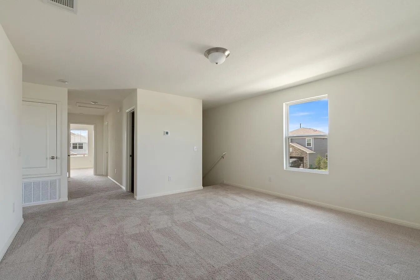 101 Aoudad Road Hutto, TX 78634 - Photo 28 of 39 A spacious upper-level area features soft carpeting and ample natural light from a prominent window.
