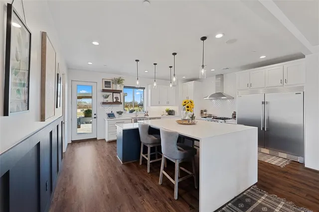a kitchen with stainless steel appliances kitchen island granite countertop a table chairs and a refrigerator