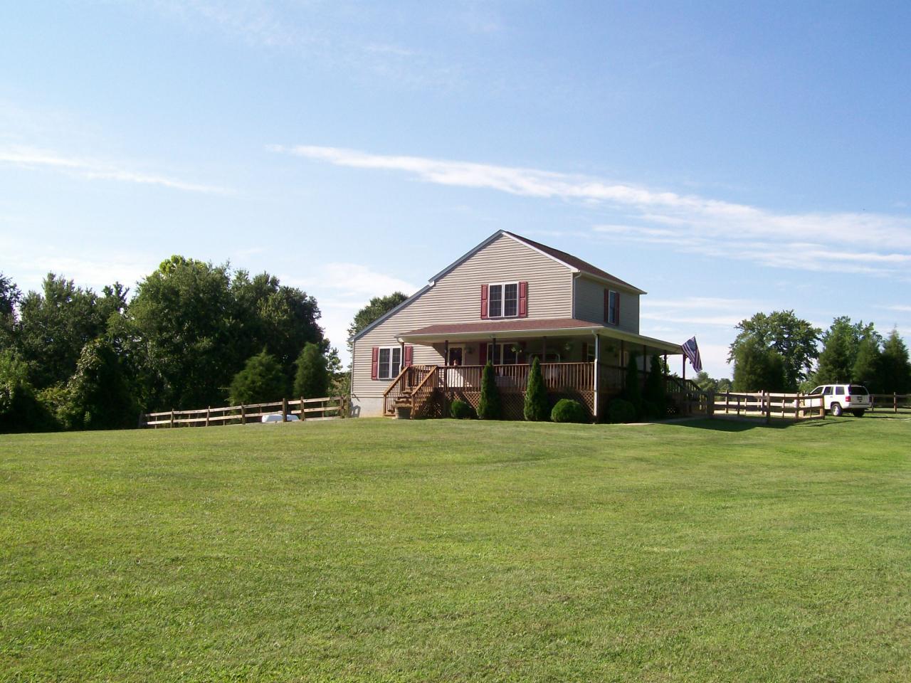 a view of a big house with a big yard and large trees