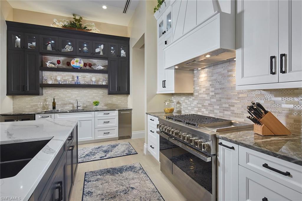 5301 Tamarind Ridge Drive Naples, FL 34119 - Photo 18 of 50 a kitchen with stainless steel appliances granite countertop a stove sink and cabinets