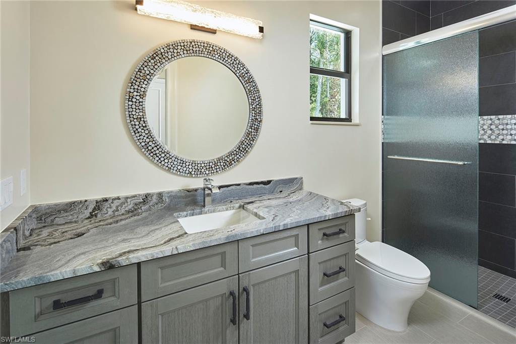 5301 Tamarind Ridge Drive Naples, FL 34119 - Photo 33 of 50 a bathroom with a granite countertop toilet a sink and mirror