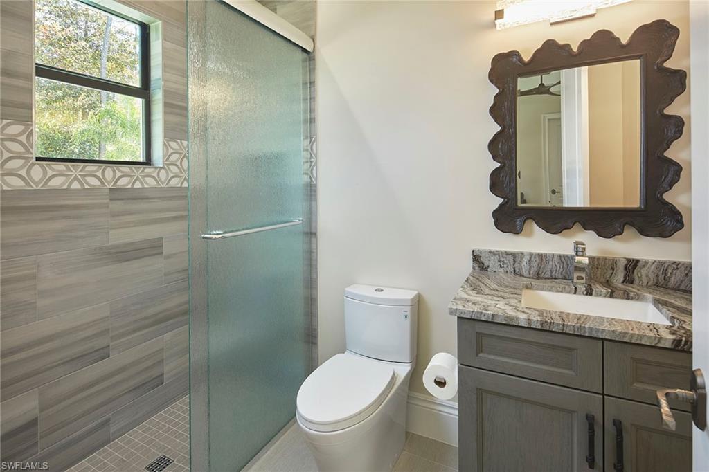 5301 Tamarind Ridge Drive Naples, FL 34119 - Photo 35 of 50 a bathroom with a granite countertop toilet sink and mirror