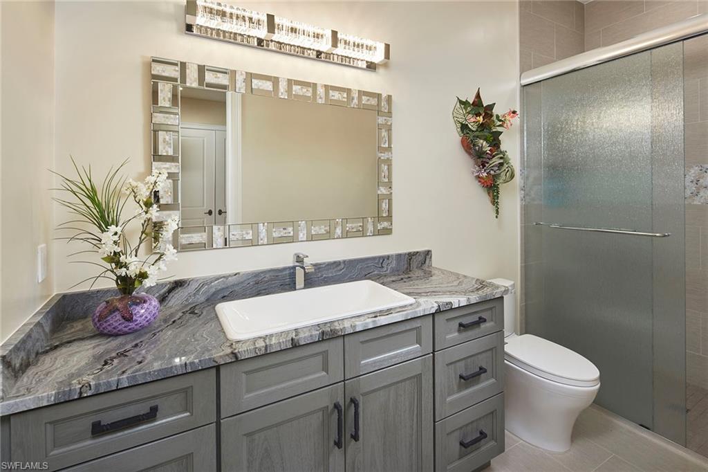 5301 Tamarind Ridge Drive Naples, FL 34119 - Photo 38 of 50 a bathroom with a granite countertop sink a toilet and mirror