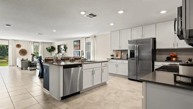 a kitchen with stainless steel appliances granite countertop a refrigerator oven a sink dishwasher and white cabinets with wooden floor