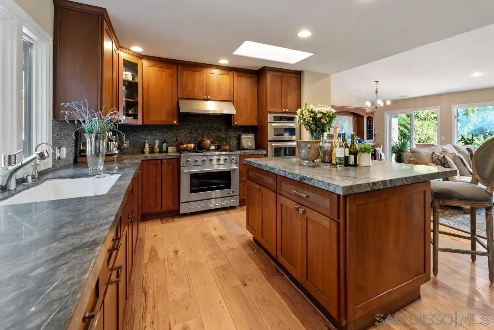 16919 Reposa Alta Rancho Santa Fe, CA 92067 - Photo 18 of 51 a kitchen with stainless steel appliances granite countertop a sink a stove and a wooden floors