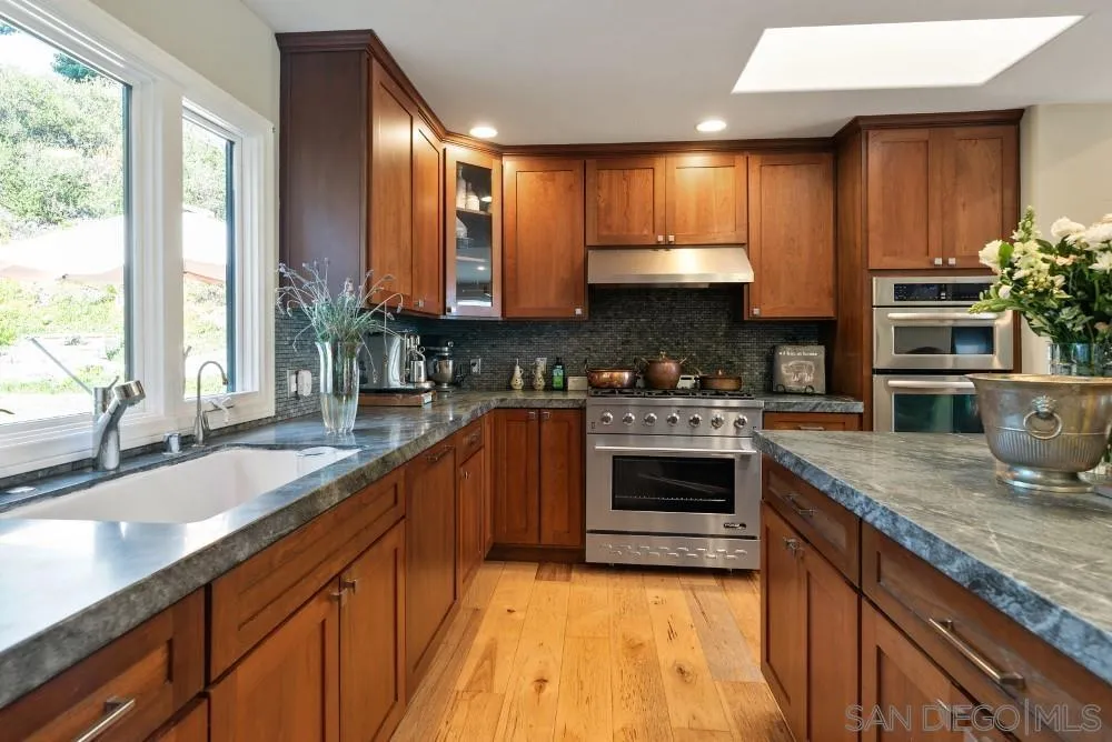 16919 Reposa Alta Rancho Santa Fe, CA 92067 - Photo 21 of 51 a kitchen with stainless steel appliances granite countertop wooden cabinets a sink and a stove