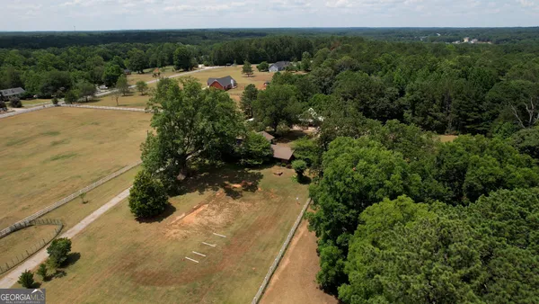 an aerial view of residential house with outdoor space and trees all around