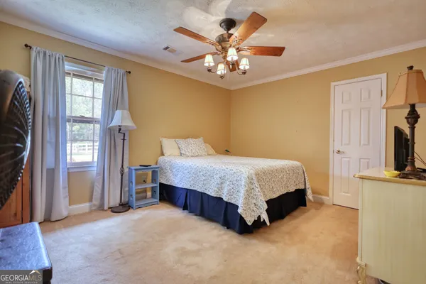 a spacious bedroom with a bed chandelier and a window