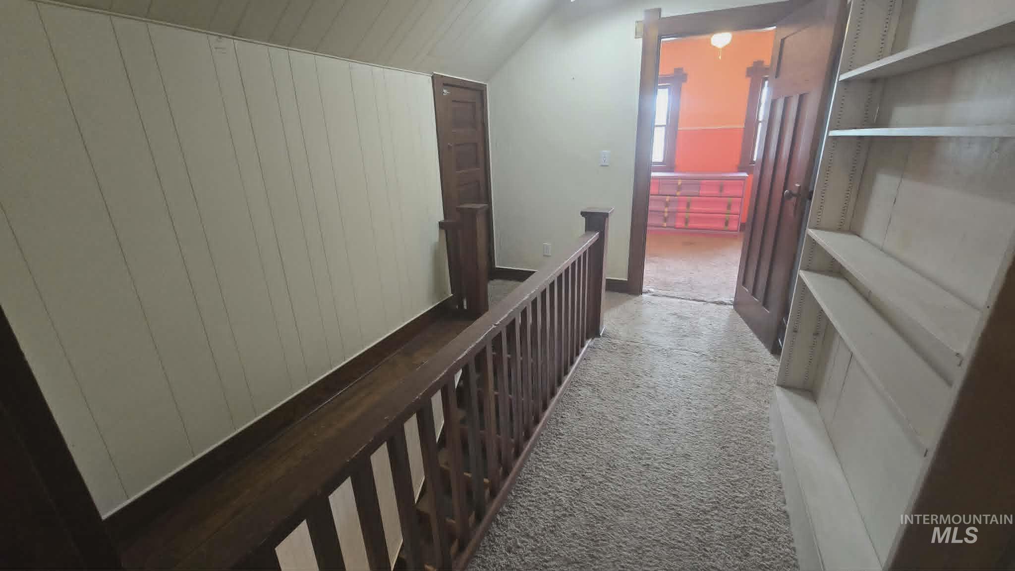 1212 Main Street Pomeroy, WA 99347 - Photo 14 of 18 Upper-level landing featuring textured carpeting, a wood-finish railing, a built-in bookcase, and a paneled wall