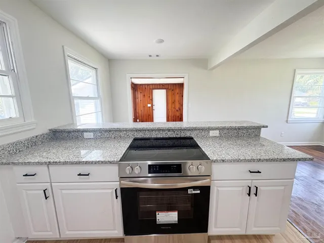 a kitchen with granite countertop a stove sink and window