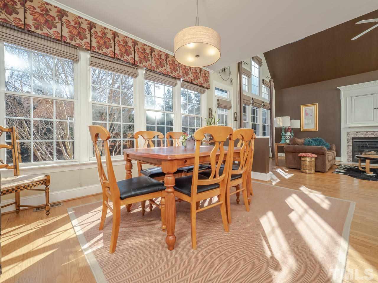 4604 Whitmire Place Raleigh, NC 27612 - Photo 10 of 25 a dining room with furniture a fireplace and large windows