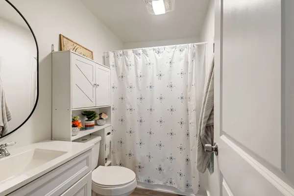 a white toilet sitting next to a bathroom sink and a shower curtain