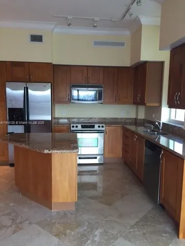 a kitchen with stainless steel appliances granite countertop a stove a sink and a refrigerator