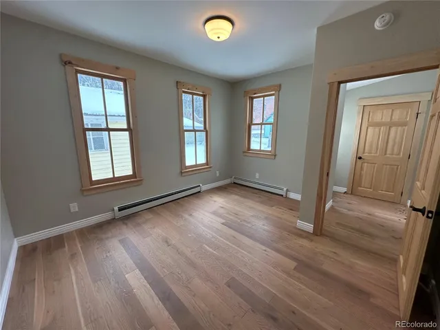 a view of an empty room with a window and wooden floor