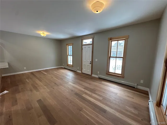 an empty room with wooden floor and windows