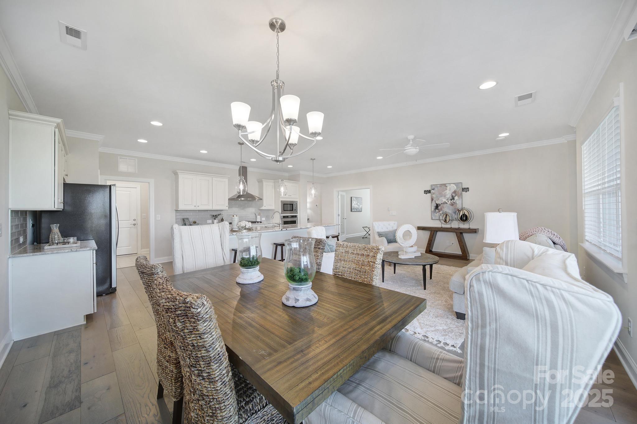 6255 Scuttle Lane, Unit 1104 Denver, NC 28037 - Photo 9 of 45 a view of a dining room and livingroom with furniture wooden floor a rug a fireplace and a chandelier