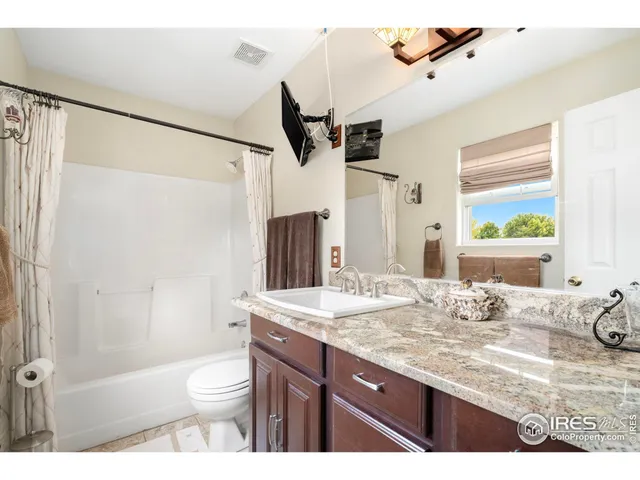 a bathroom with a granite countertop sink toilet mirror and shower