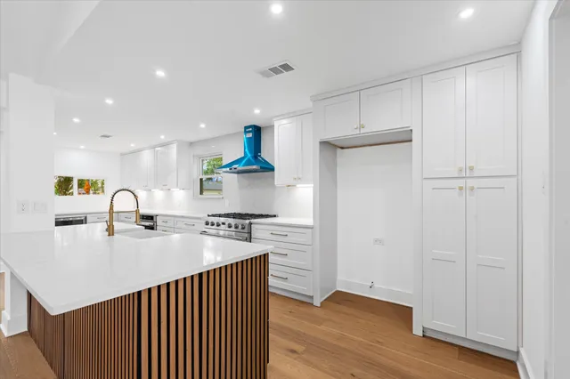 a kitchen with a sink a stove cabinets and wooden floor