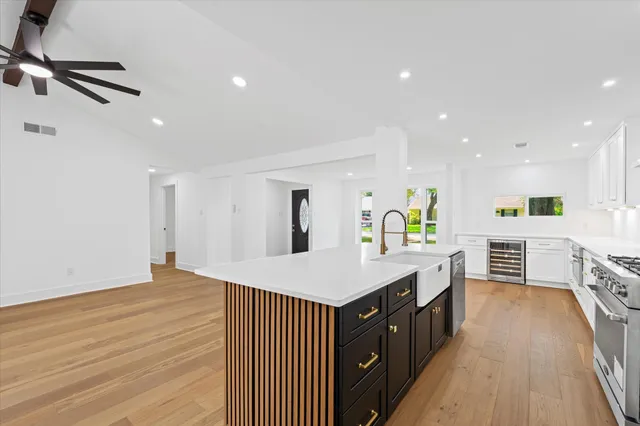 a large kitchen with stainless steel appliances a large counter top a stove a sink and a refrigerator