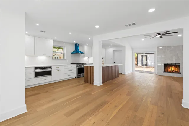 a view of kitchen with granite countertop a stove top oven a sink dishwasher and a fireplace with wooden floor