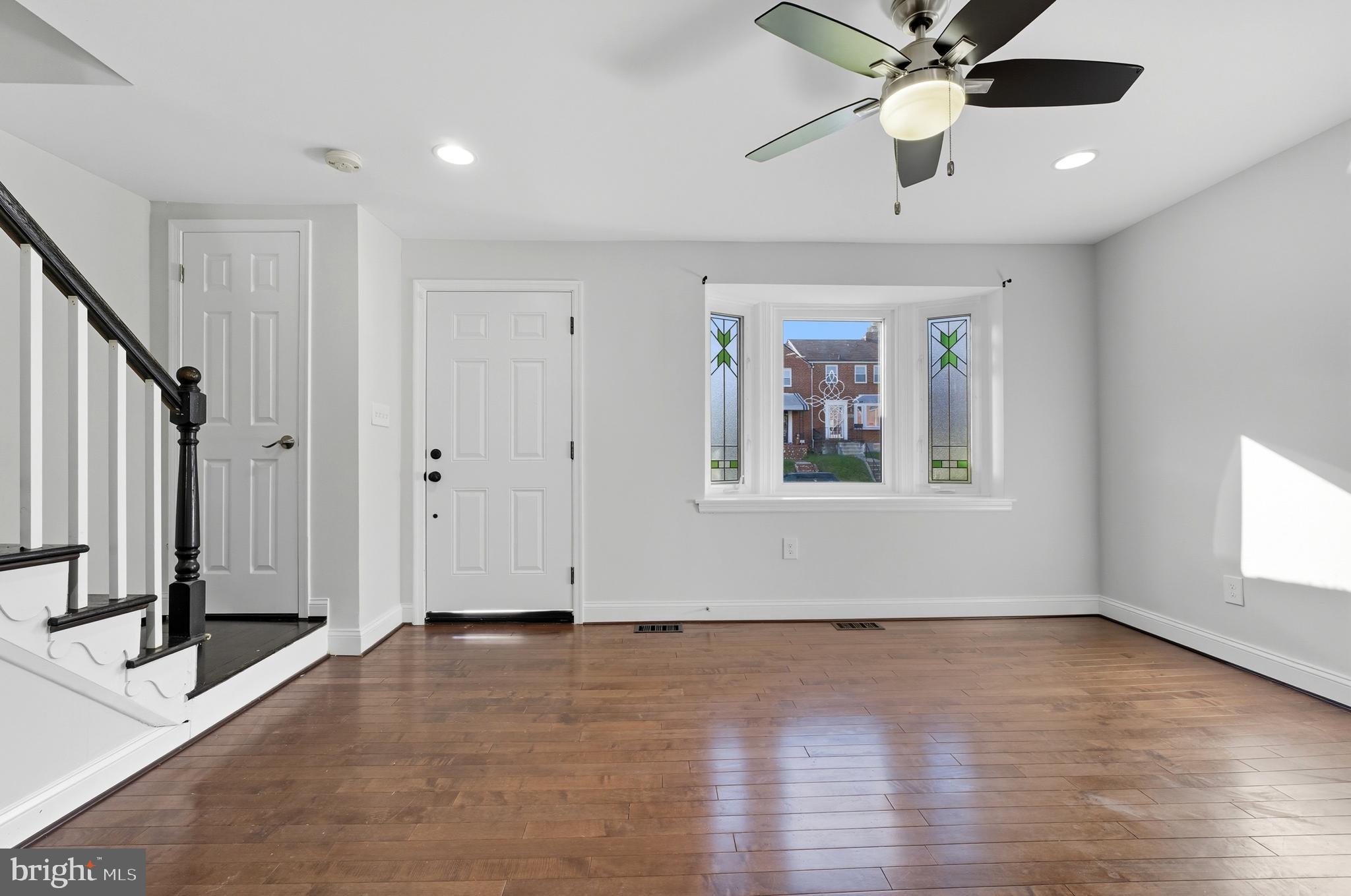 5768 Maplehill Road Baltimore, MD 21239 - Photo 2 of 29 an empty room with wooden floor fan and windows