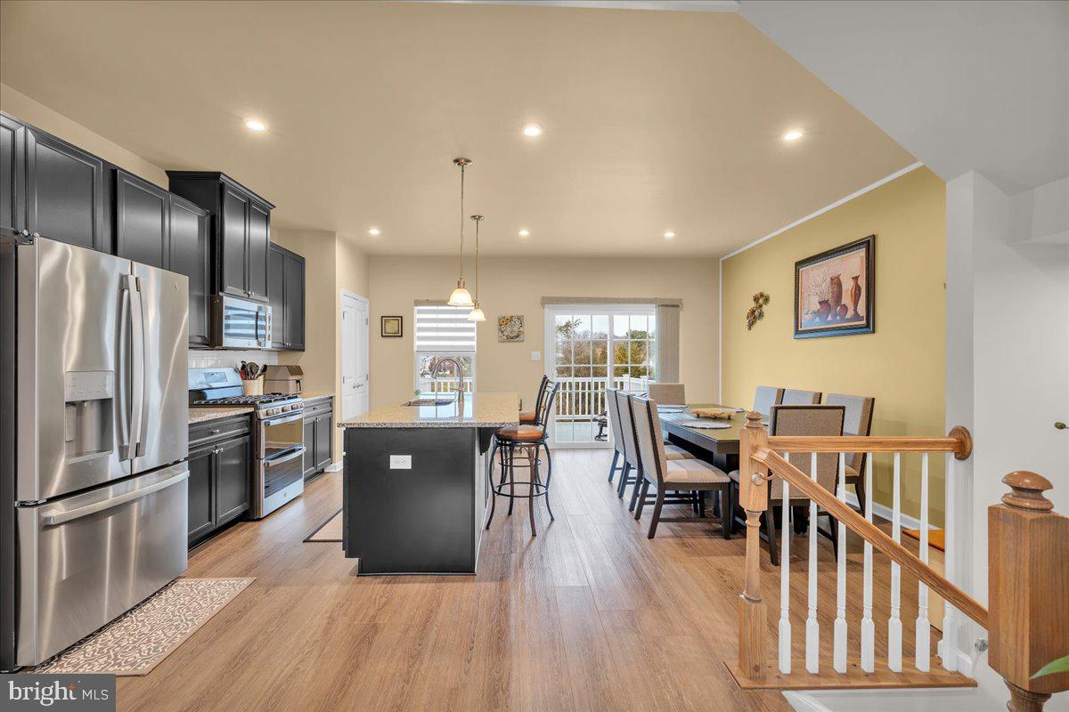 204 Freedom Way Sicklerville, NJ 08081 - Photo 11 of 32 a kitchen with stainless steel appliances granite countertop a refrigerator a stove a sink a dining table and chairs with wooden floor