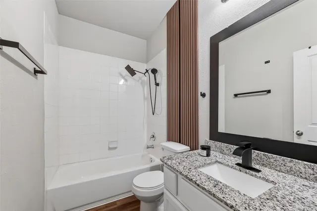 a bathroom with a granite countertop sink toilet mirror and shower