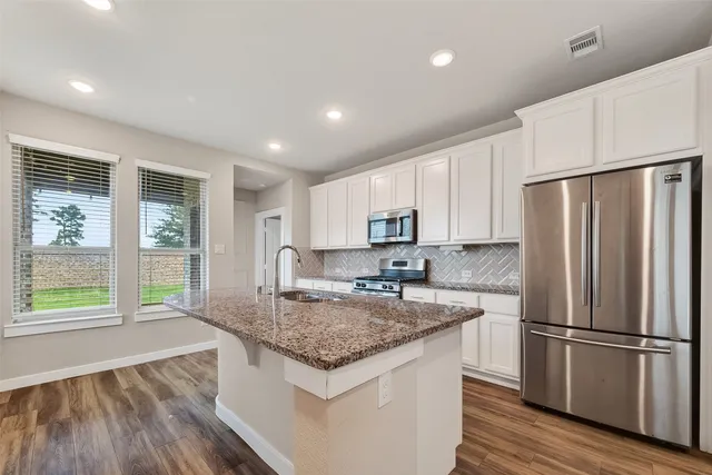 a kitchen with stainless steel appliances granite countertop a refrigerator a sink dishwasher a stove and a refrigerator with wooden floor