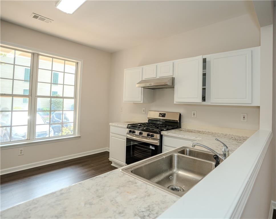 4645 Valais Court, Unit 109 Alpharetta, GA 30022 - Photo 7 of 27 a kitchen with granite countertop a sink and a stove top oven