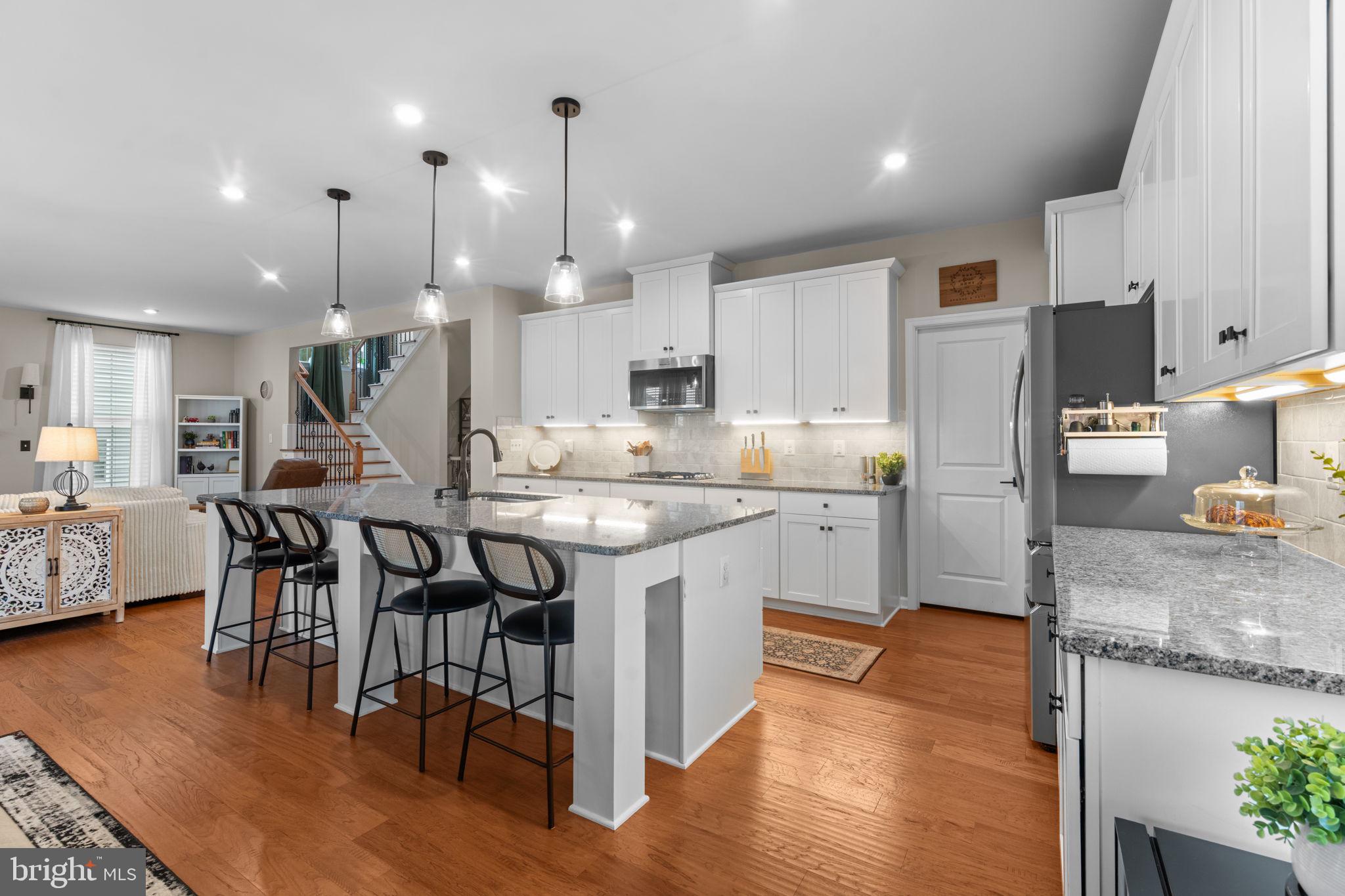 12432 Mays Quarter Road Woodbridge, VA 22192 - Photo 23 of 94 a kitchen with stainless steel appliances granite countertop a stove top oven a sink a refrigerator and white cabinets with wooden floor