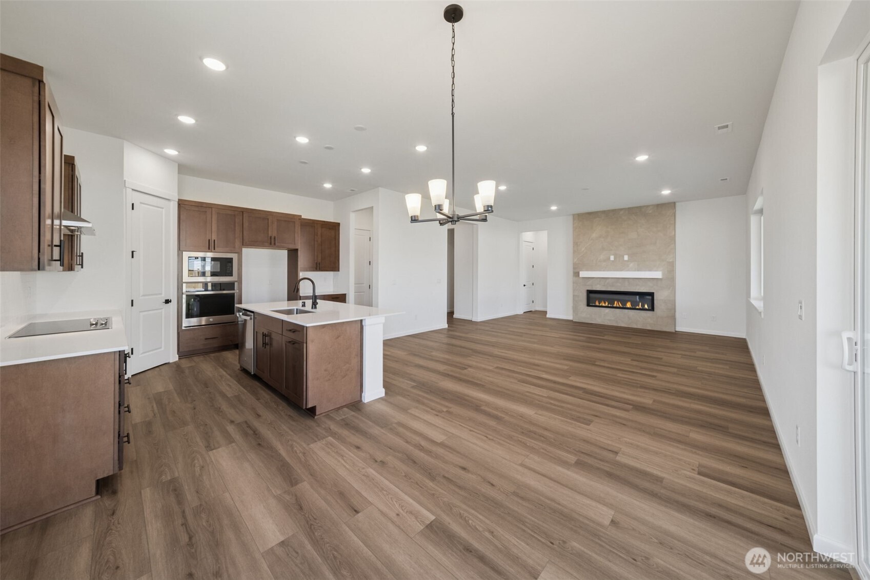 932 Lucas Avenue, Unit 21 Buckley, WA 98321 - Photo 20 of 30 a open kitchen with kitchen island a stove a sink dishwasher a refrigerator and a fireplace with wooden floor