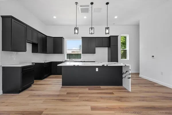 a kitchen with stainless steel appliances granite countertop a refrigerator a stove a sink and a oven with wooden floor