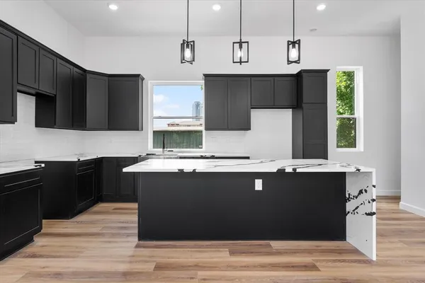 a kitchen with kitchen island stainless steel appliances a sink stove refrigerator and cabinets