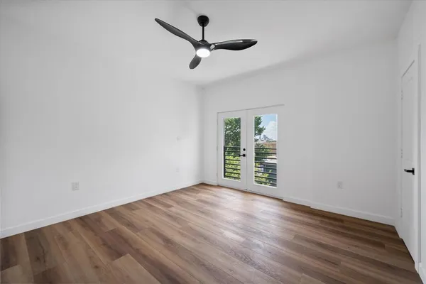 an empty room with wooden floor a ceiling fan and windows