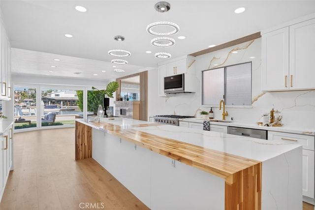 a large kitchen with a large counter top a sink stainless steel appliances and cabinets