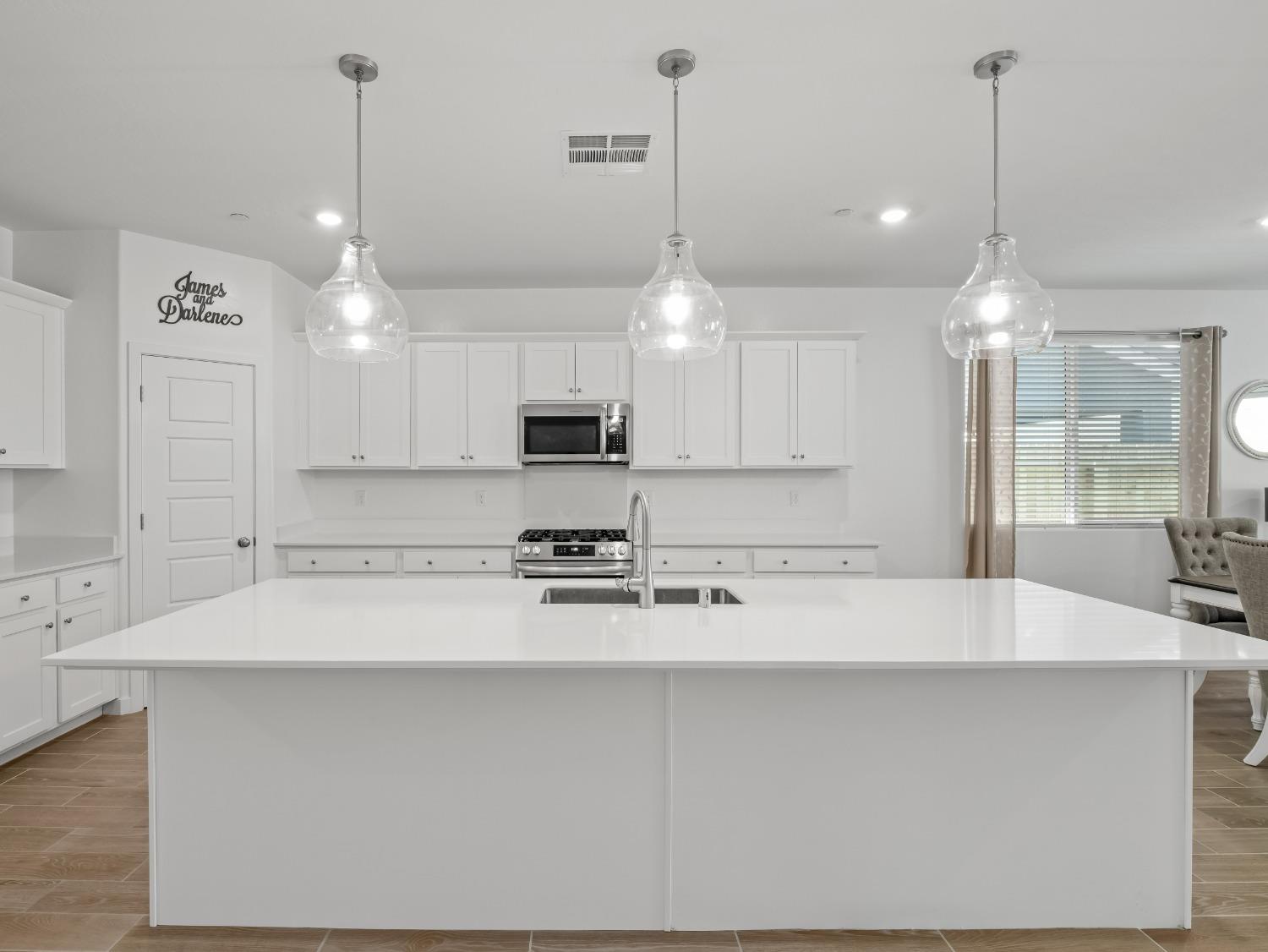 2682 Highland Avenue Clovis, CA 93619 - Photo 5 of 29 a large kitchen with kitchen island a stove a sink a center island a refrigerator and a living room view