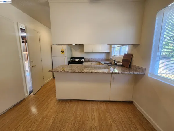 a living room with stainless steel appliances granite countertop furniture and a wooden floor