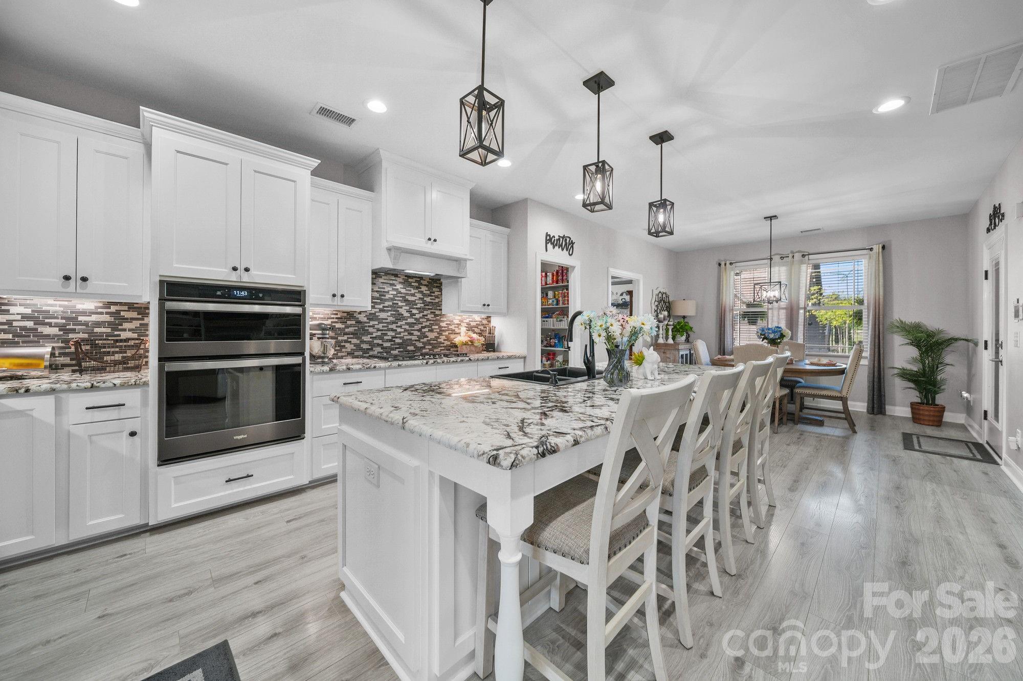 617 Caudle Road Peachland, NC 28133 - Photo 14 of 48 a kitchen with stainless steel appliances kitchen island granite countertop a stove top oven a sink a dining table and chairs with wooden floor