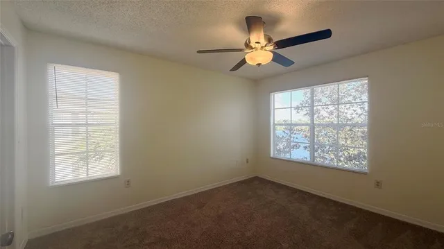 an empty room with windows and fan