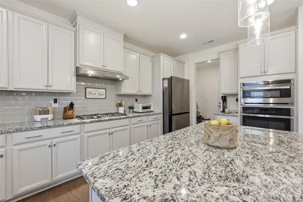 a kitchen with stainless steel appliances granite countertop a refrigerator sink stove microwave and cabinets