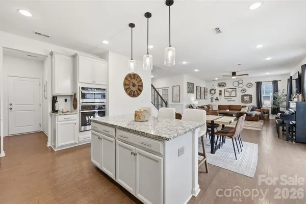 a kitchen with stainless steel appliances kitchen island granite countertop a table chairs and a view of living room