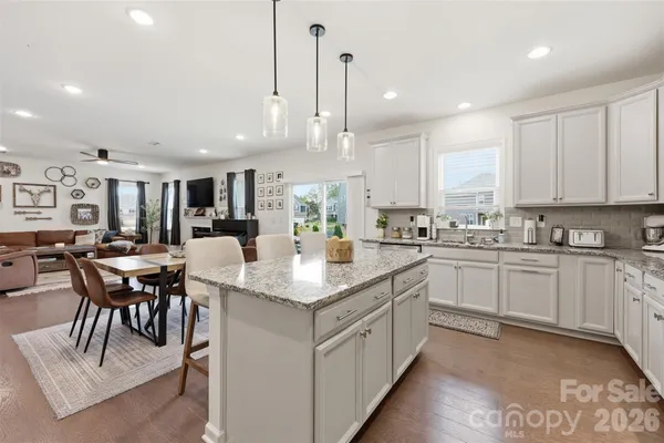 a kitchen with kitchen island granite countertop a table chairs sink and cabinets