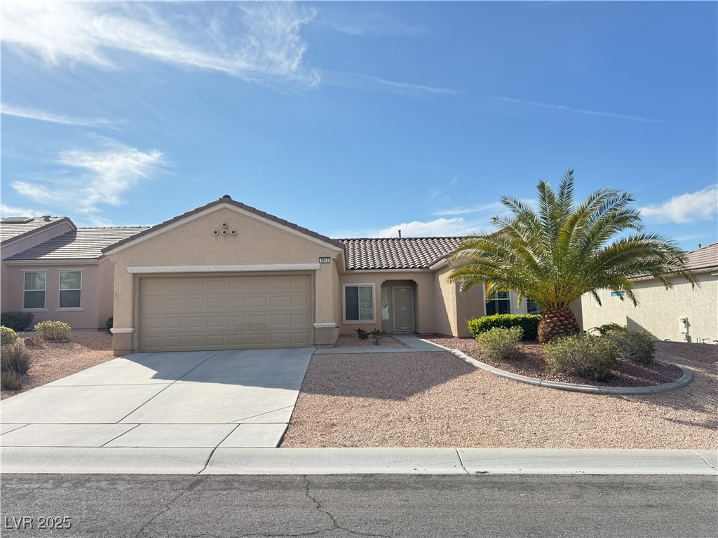 View of front of home featuring driveway, stucco siding, and a tiled roof